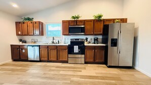 A modern kitchen with wooden cabinets, stainless steel appliances, and a dishwasher.