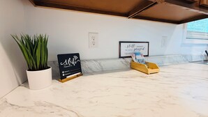 A marble countertop with a potted plant, a signboard with a WiFi password, a framed quote, and a wooden box with items.