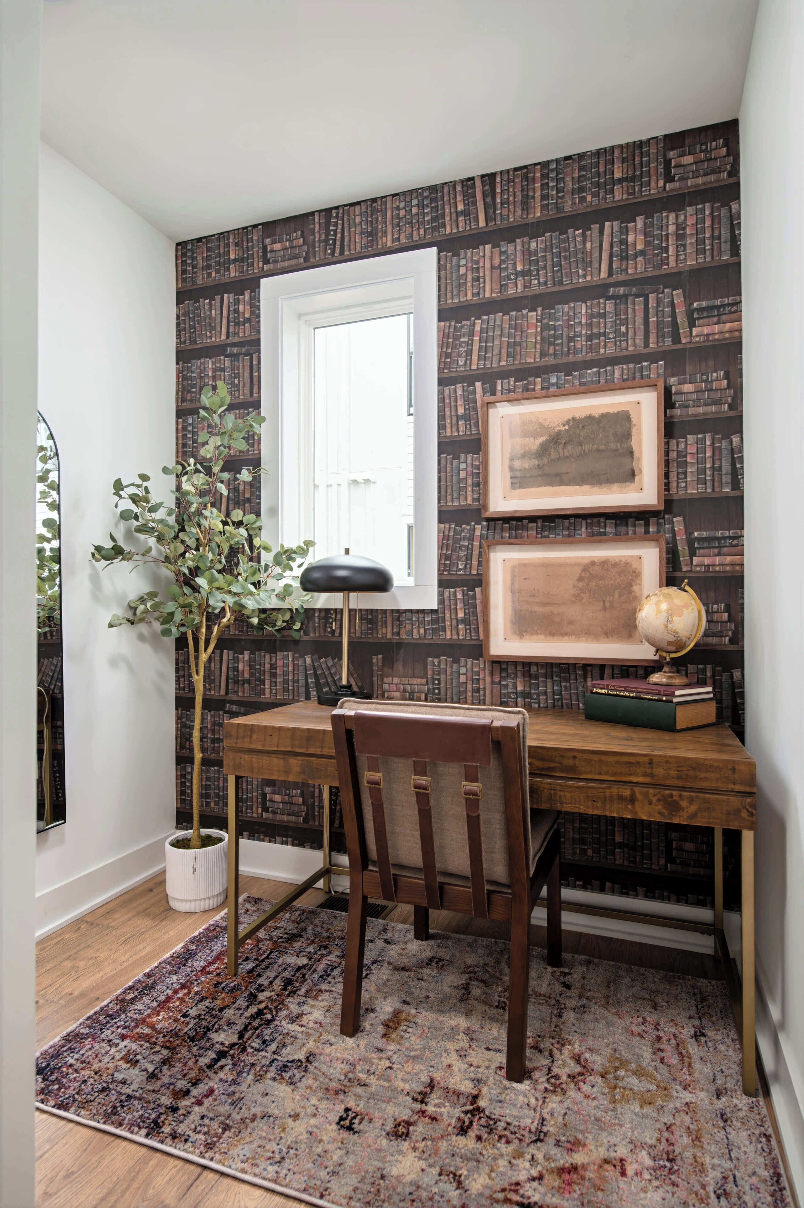 Un salón de estudio con un escritorio de madera, una silla, un globo terráqueo, cuadros enmarcados y una estantería contra la pared.