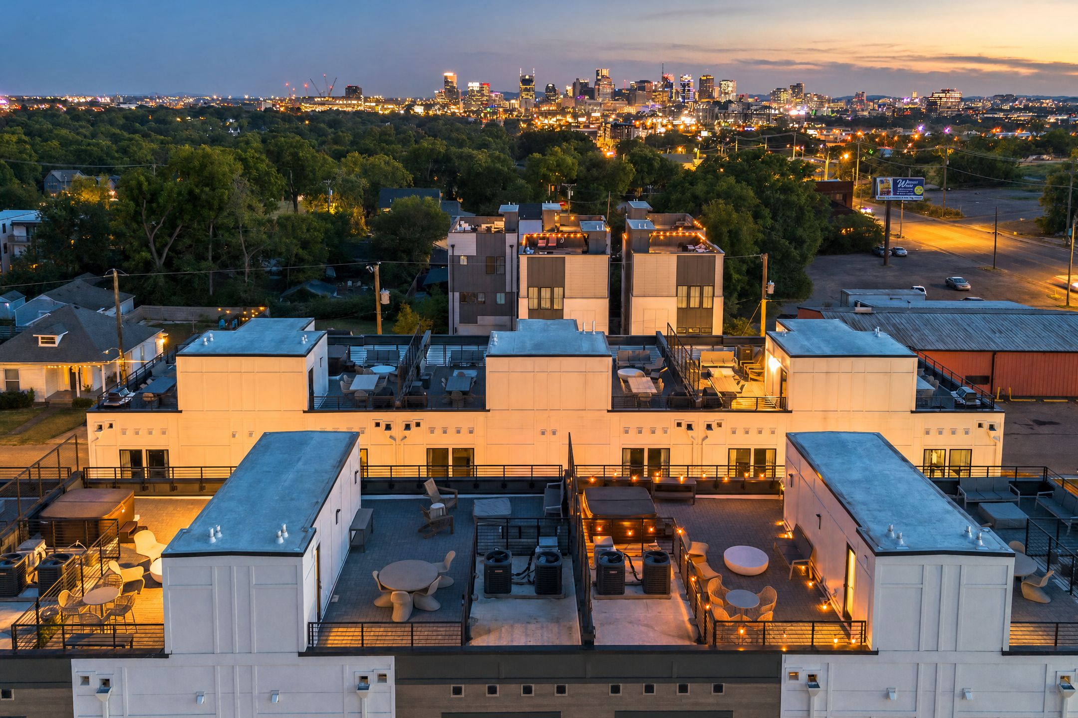 A multi-story building with rooftop terraces featuring outdoor seating and ambient lighting.