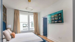 Quarto de hotel moderno com uma cama, cortinas, televisão e vista para o exterior.