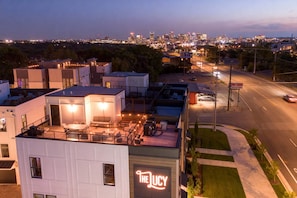 Ein modernes Gebäude mit Dachterrasse und einer Neonreklame mit der Aufschrift 'The Lucy'.