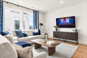 A modern living room with a sofa, coffee table, and a flat-screen TV mounted on the wall.