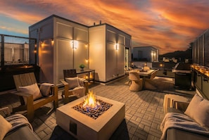 A rooftop patio with outdoor seating, a fire feature, and ambient lighting.