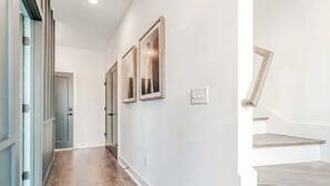 A hallway with wooden flooring, white walls, and a staircase with wooden steps. - Nashville 4-bedroom house with gas grill, sleeps 12, pet friendly (Nashville)