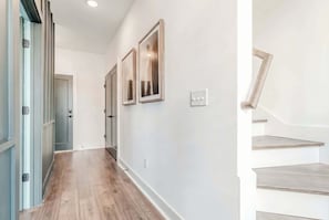 A hallway with wooden flooring, white walls, and a staircase with wooden steps.