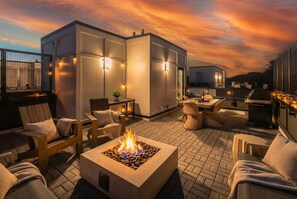 A rooftop patio with outdoor seating, a fire feature, and ambient lighting.
