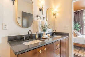 A modern bathroom with two sinks, a large mirror, and wall-mounted lights. - Fall getaway: 4BR Nashville home with gold-tile shower, sleeps 12 (Nashville)
