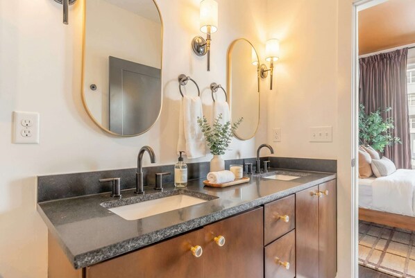 A modern bathroom with two sinks, a large mirror, and wall-mounted lights. - Fall getaway: 4BR Nashville home with gold-tile shower, sleeps 12 (Nashville)