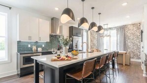 A modern kitchen with a central island, pendant lighting, and bar stools. - Nashville 4-bedroom house with gas grill, sleeps 12, pet friendly (Nashville)