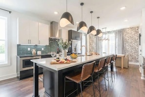 A modern kitchen with a central island, pendant lighting, and bar stools.