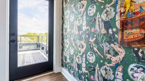 A room with a black door leading to a balcony, a green wall with comic book-style wallpaper, and a colorful patterned area on the right. - Nashville 4-bedroom house with gas grill, sleeps 12, pet friendly (Nashville)