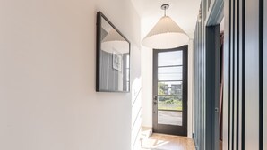 A hallway with a door leading to a balcony, a mirror on the wall, and a ceiling light fixture. - Weekend getaway: private hot tub, 4 bedrooms, sleeps 12 near Nashville (Nashville)