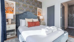 A modern bedroom with a large bed, two bedside tables, a headboard, and a patterned wall. - Weekend getaway: private hot tub, 4 bedrooms, sleeps 12 near Nashville (Nashville)