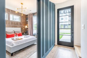 Ein modernes Hotelzimmer mit Bett, Nachttisch, Lampe und Blick nach draußen.