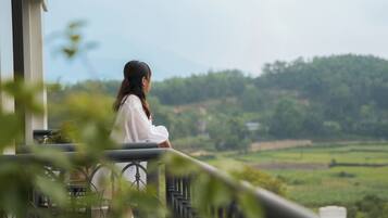 A person sitting on a balcony overlooking a green landscape.