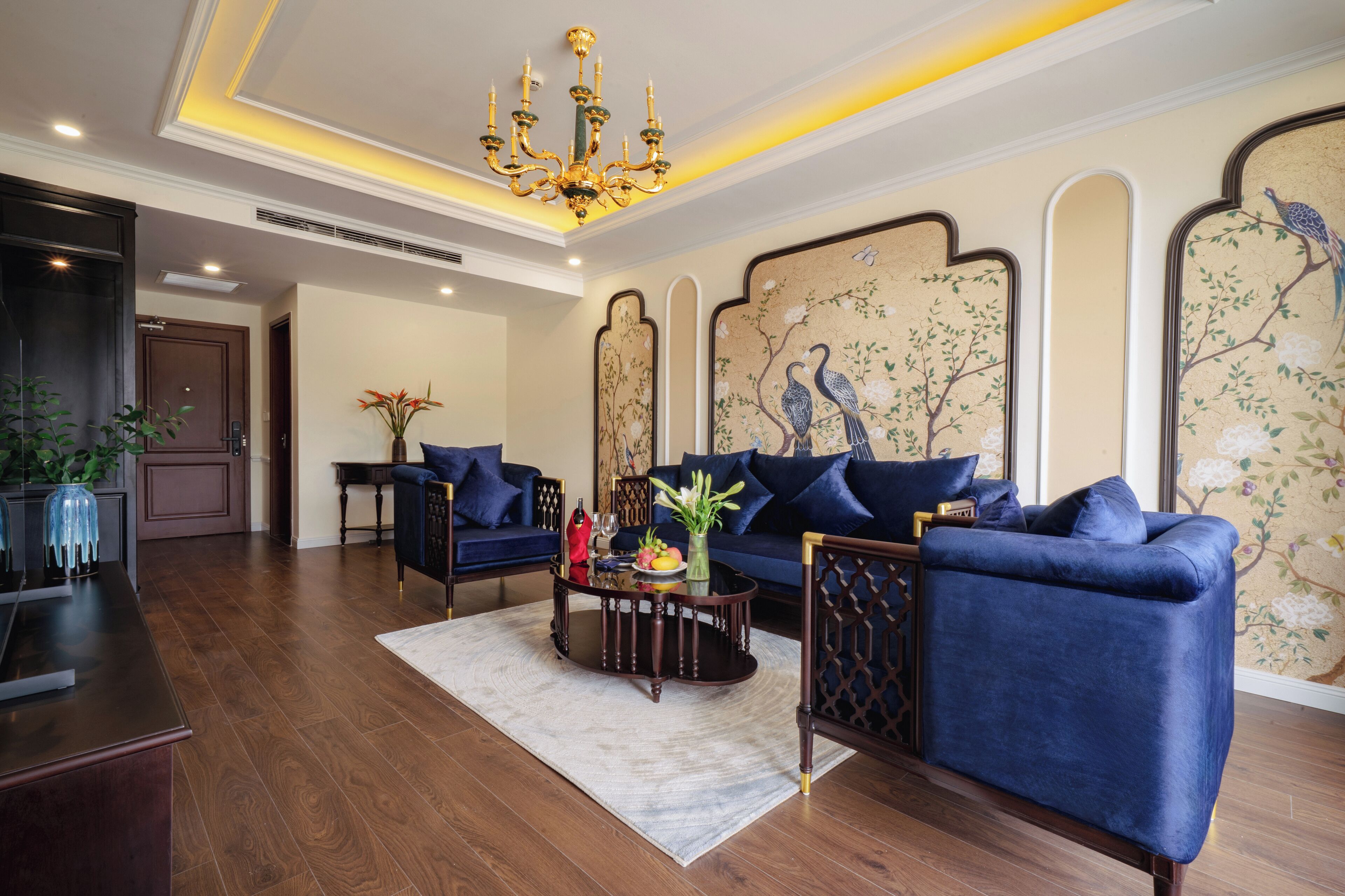 A spacious living room with a blue sofa, a coffee table, and a chandelier.