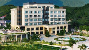 A multi-story hotel with a central courtyard, surrounded by lush greenery and mountains. - Venusgiti Hot Spring Resort & Spa  (Kim Boi)