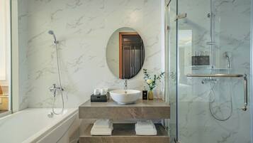 Une salle de bain moderne avec une baignoire, un miroir rond, un lavabo et une douche à parois de verre.