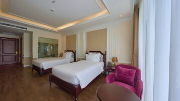 A hotel room with two beds, a sitting area with a chair and table, and a large mirror.