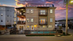 A multi-story building with balconies, a swimming pool, and a gated entrance. - Iconic 8BR w/ Rooftop Deck, Pool & Spa | Sleeps 24 (North Myrtle Beach)