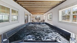 A spa area with a hot tub, wooden ceiling beams, and large windows. - Iconic 8BR w/ Rooftop Deck, Pool & Spa | Sleeps 24 (North Myrtle Beach)
