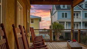 A wooden deck with chairs, a small table, and a view of neighboring houses. - Iconic 8BR w/ Rooftop Deck, Pool & Spa | Sleeps 24 (North Myrtle Beach)