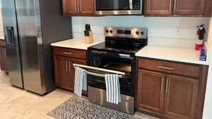 A kitchen with stainless steel appliances, wooden cabinets, and a patterned rug.