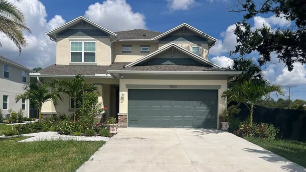 A two-story house with a garage, surrounded by well-maintained lawns and small trees.