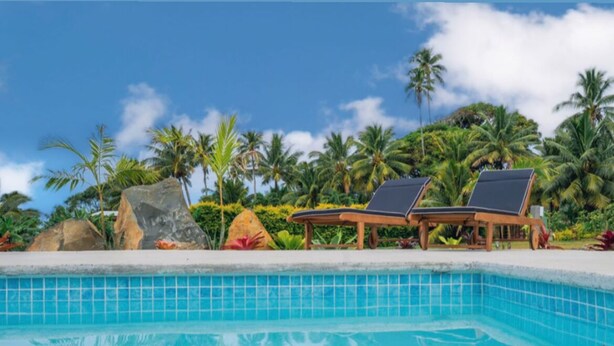A pool with two lounge chairs, surrounded by tropical vegetation and palm trees. - Enua Tipani Pool Villa
• Quiet • Convenient location• Modern Finishes • Sleeps 8 (Rarotonga)
