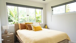 A bedroom with a large bed, a nightstand, and a window with a view of greenery. - Enua Tipani Pool Villa
• Quiet • Convenient location• Modern Finishes • Sleeps 8 (Rarotonga)