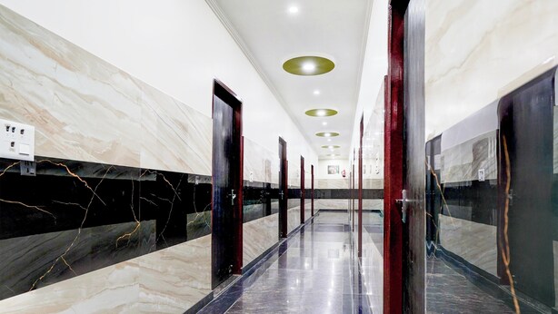 Un pasillo con paredes y pisos de mármol, iluminación empotrada y puertas con paneles de vidrio.