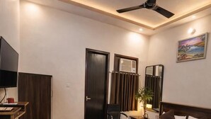 Una habitación de hotel moderna con una cama, un escritorio, una silla, un televisor y un ventilador de techo.