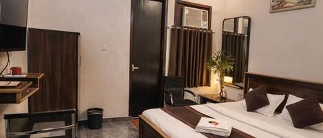 A modern hotel room with a bed, a desk, a chair, a television, and a ceiling fan.