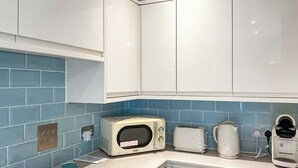 A kitchen with white cabinets, a microwave, a toaster, and a coffee maker on the counter. - 1 bedroom accommodation in St Athan , near Cardiff (St Athan , near Cardiff)