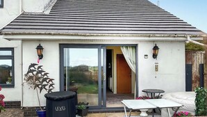 A house with a tiled patio, a black outdoor exercise station, a white sofa, and a dining table. - 1 bedroom accommodation in St Athan , near Cardiff (St Athan , near Cardiff)