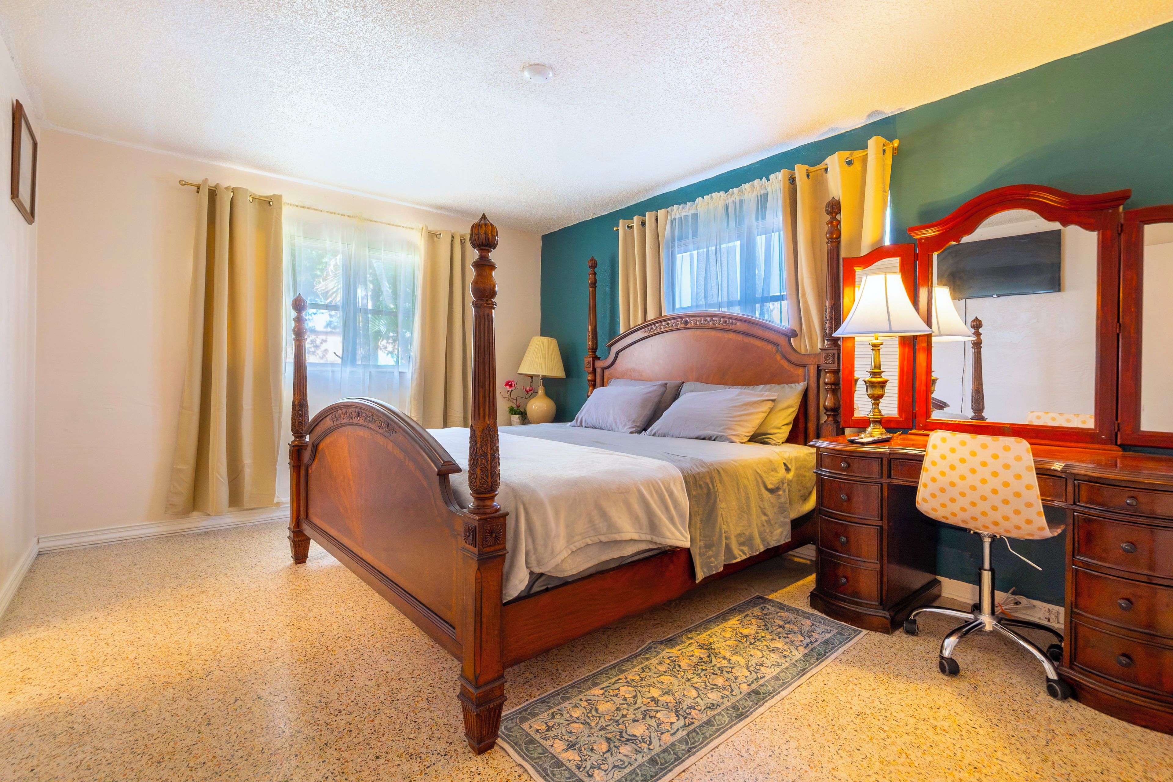 Une chambre à coucher avec un lit à baldaquin, un bureau avec une chaise et un grand miroir.