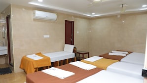 A hotel room with three beds, a bathroom, and a ceiling fan. - SSR HOTEL (Srikalahasti)