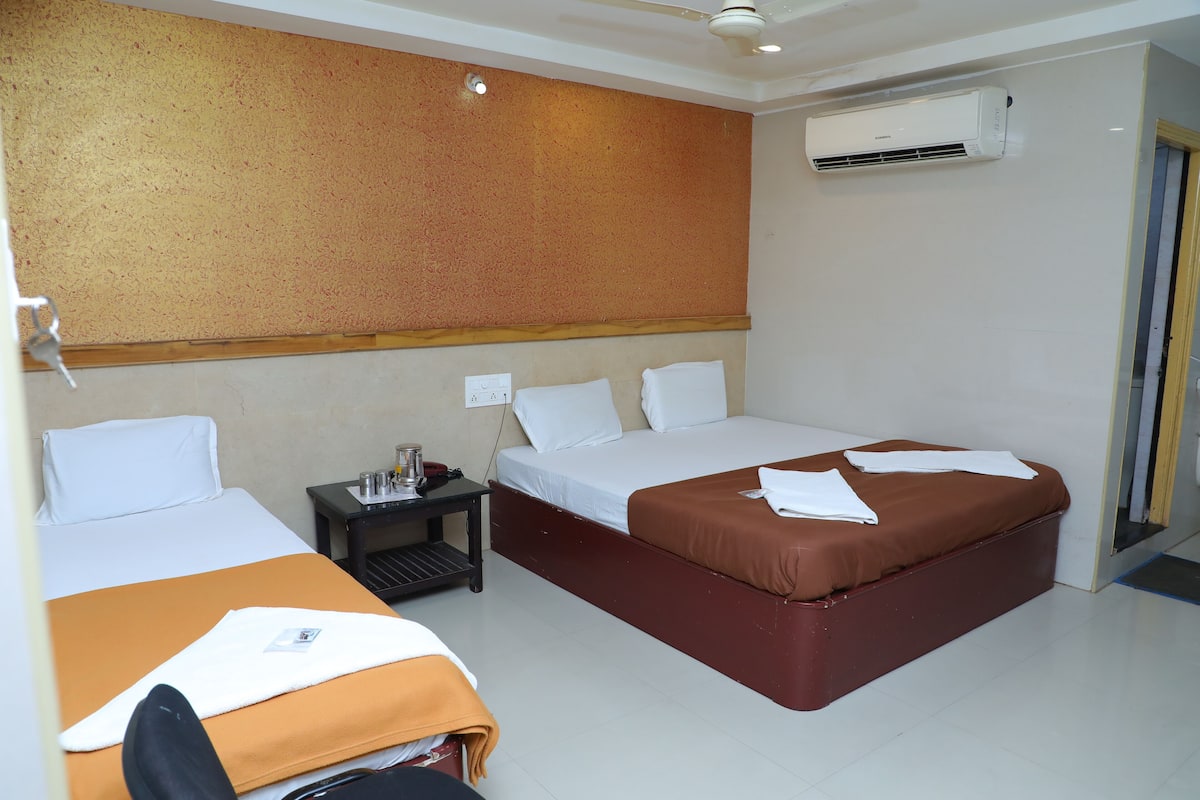 Habitación de hotel con dos camas, una mesita de noche, un equipo de aire acondicionado y un ventilador de techo.