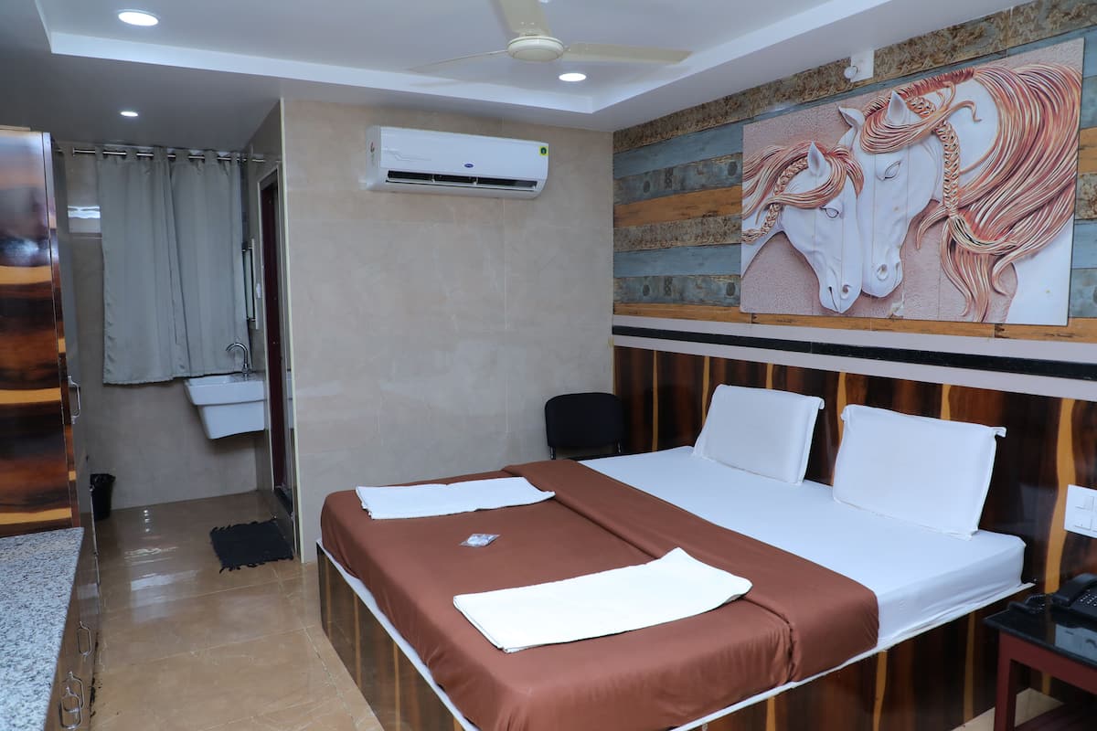 Habitación de hotel con cama, escritorio con teléfono, equipo de aire acondicionado, pintura de caballos y baño con cortina de ducha.
