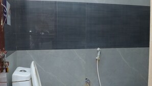 A bathroom with a toilet, a shower, and a small window. - SSR HOTEL (Srikalahasti)
