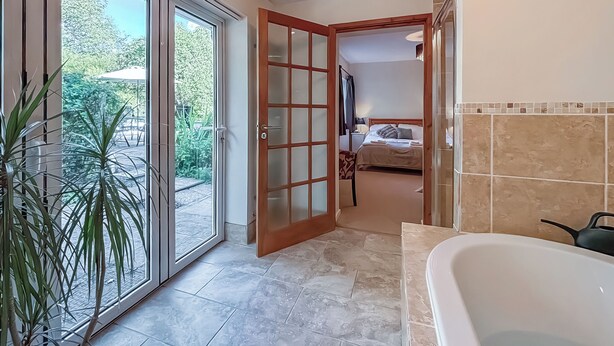 A hotel bathroom with a bathtub, a shower, and a toilet. There is a window with a view of the outdoors. - 4 bedroom accommodation in Welshpool (Welshpool)