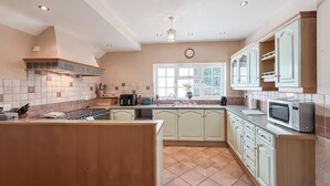 A kitchen with a central island, white cabinets, and a window with a view. - 4 bedroom accommodation in Welshpool (Welshpool)
