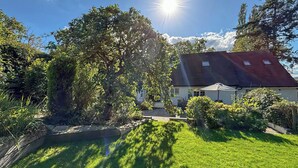 A house with a red roof, surrounded by lush greenery and a well-maintained lawn. - 4 bedroom accommodation in Welshpool (Welshpool)