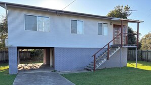 Une maison de plain-pied avec un garage, un petit porche et un escalier menant à un balcon situé au deuxième étage.