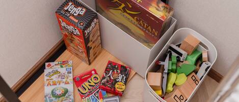 A tabletop with various board games, including Jenga, Catan, and UNO, along with a box of Mahjong tiles.