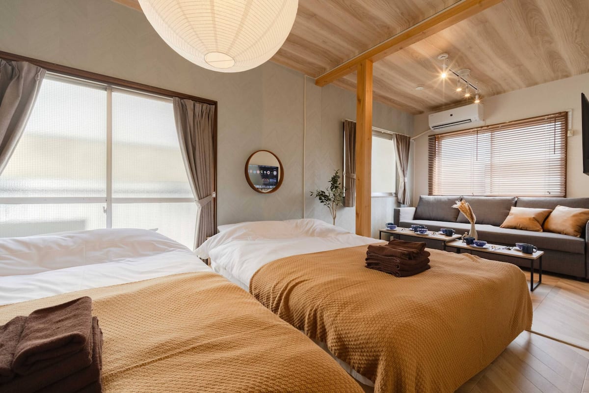 A hotel room with two beds, a sofa, a coffee table, and a TV.