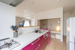 A modern kitchen with a white countertop, stainless steel sink, and a gas stove.