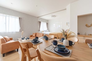 Una habitació d'hotel moderna amb zona de menjador, sofà, llit i vistes a la ciutat.