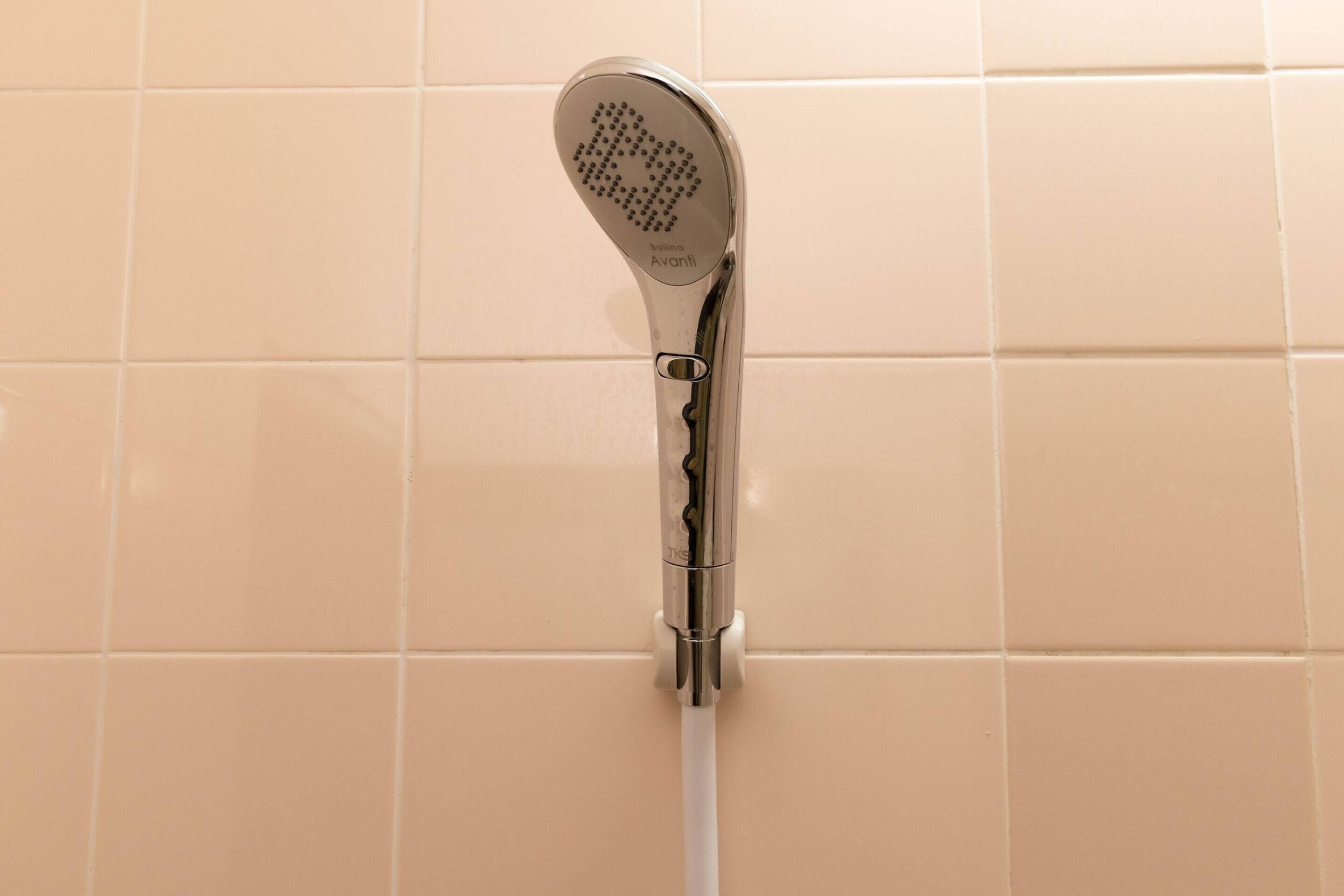 A showerhead mounted on a wall with a white pipe.